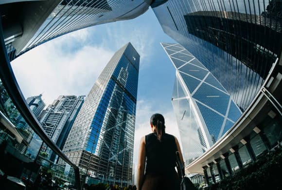 Femme qui regarde vers le ciel au centre de plusieurs buildings