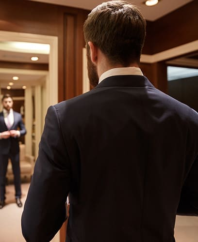 Homme devant un miroir essayant un costume