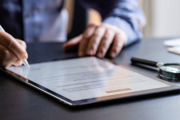 Main d'un homme qui signe un contrat d'assurance vie ou capitalisation électroniquement sur une tablette