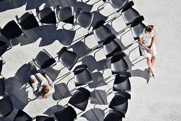 chaises rangées en forme d'escargot avec une femme assise au centre et une autre femme assise à l'extrémité