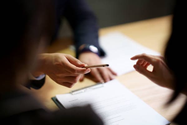 personne tendant un stylo à une autre personne face à elle afin de signer un contrat